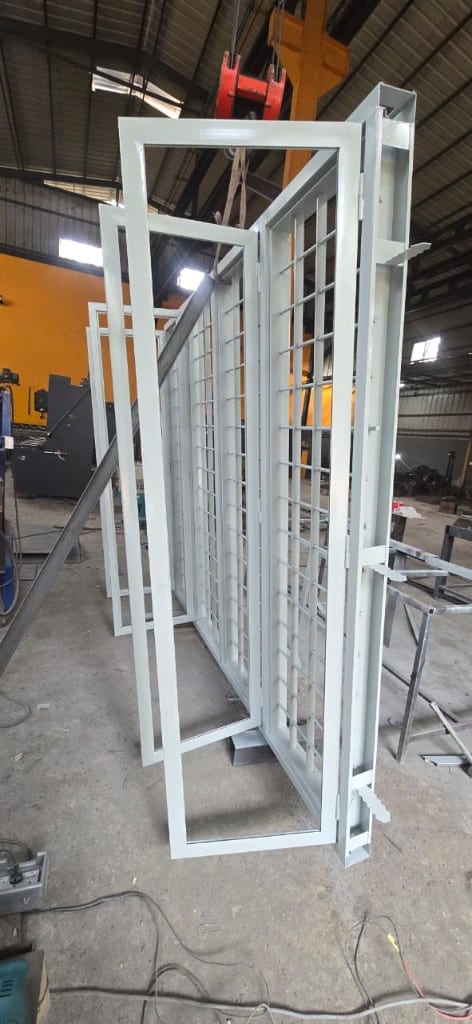 Side view of grilled steel window frames hanging from the plant crane