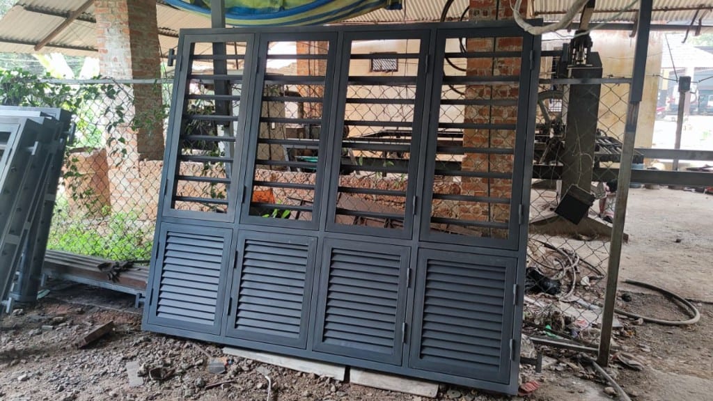 Finished steel window and door unit with louvres, mesh, and lower vents, standing in the yard